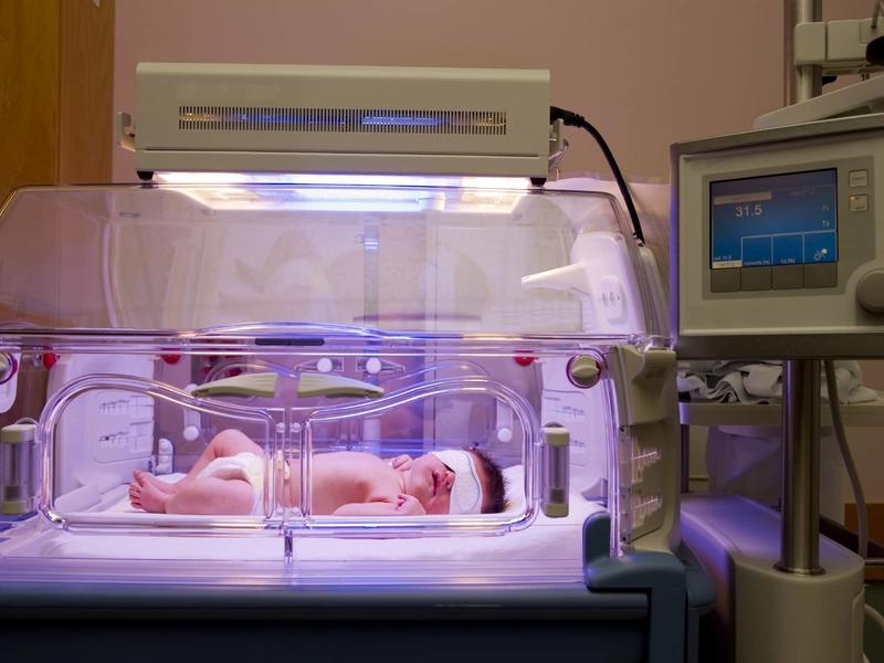 infant in the neonatal intensive care unit under a lamp