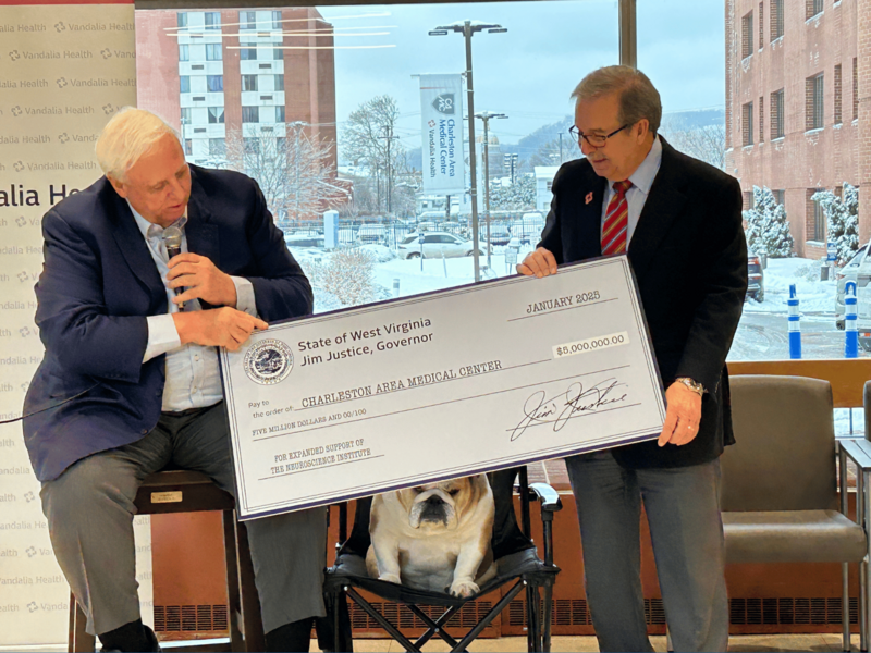 Governor Jim Justice handing Dave Ramsey a check for the new Vandalia Health Neuroscience Institute